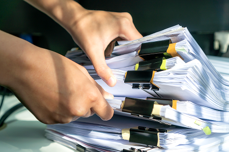 Woman examining large amounts of paperwork at a desk, symbolizing gathering and reviewing evidence in a civil sexual assault claim.