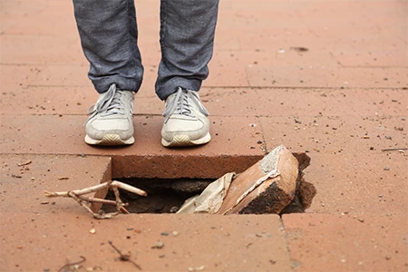 A person standing near a broken walkway brick